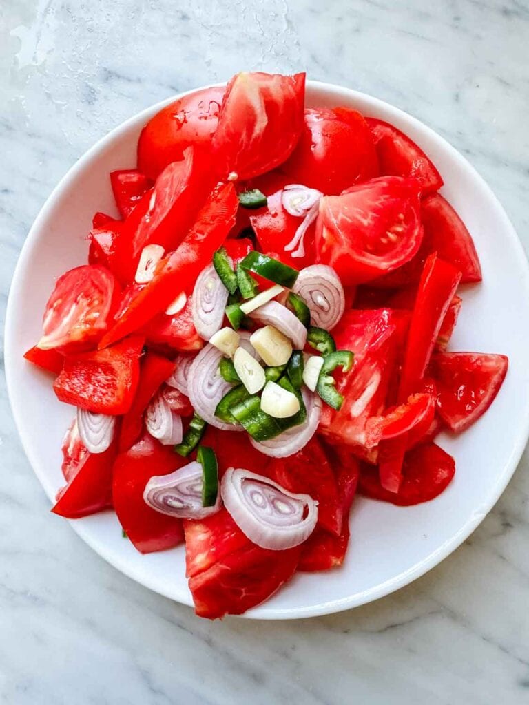 Chopped tomatoes in bowl wiht shallots. garlic and jalapeños.