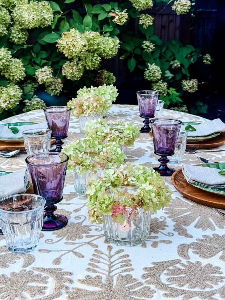 A fall dinner table is set and running down the middle are flower crown votives giving off a warm evening glow.