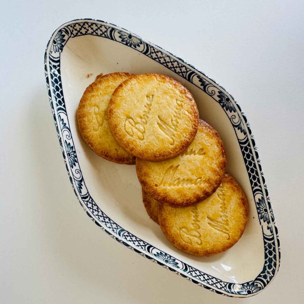 Small diamond shape dish with blue trim and cookies inside the dish.
