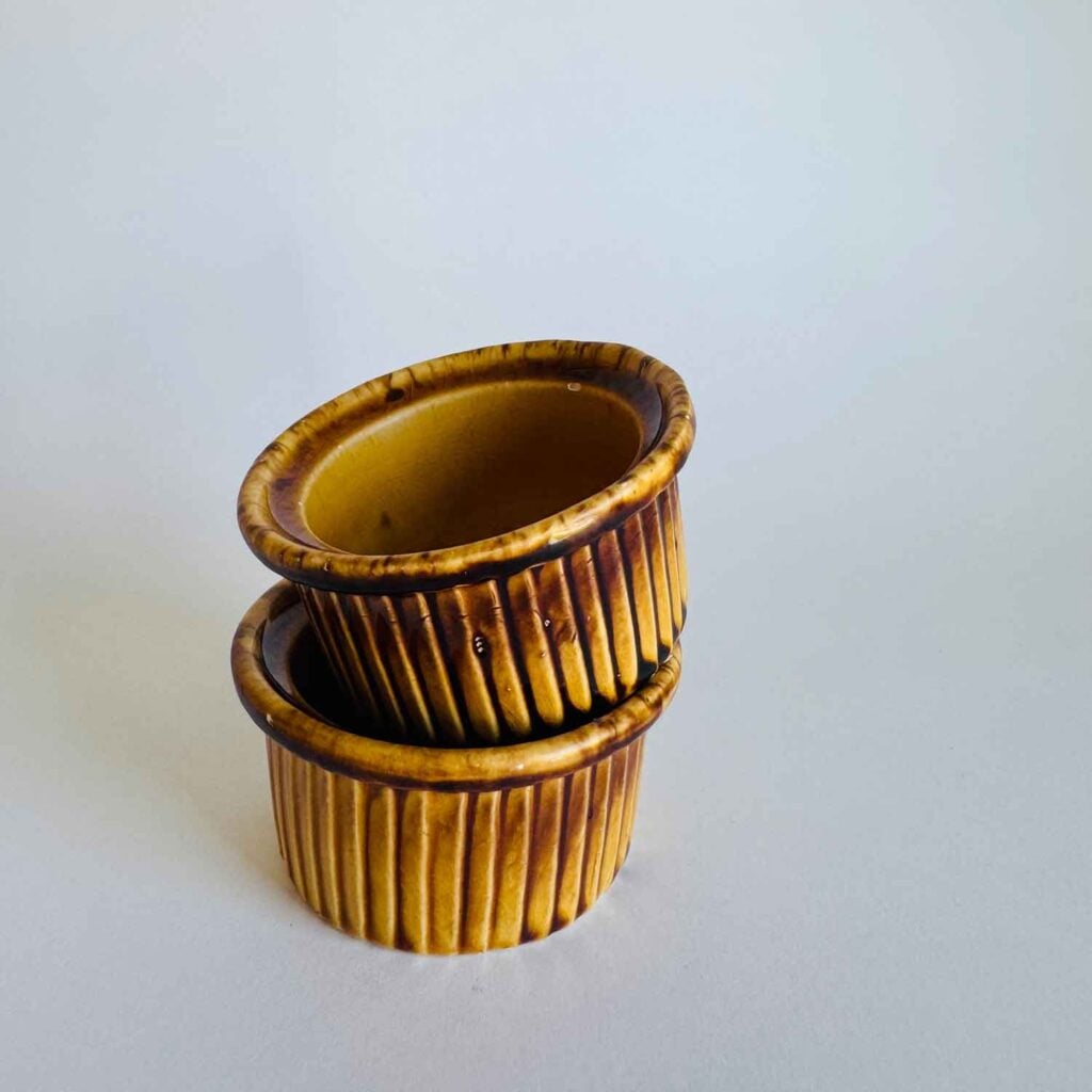 Small ramekins in harvest gold color stacked. 