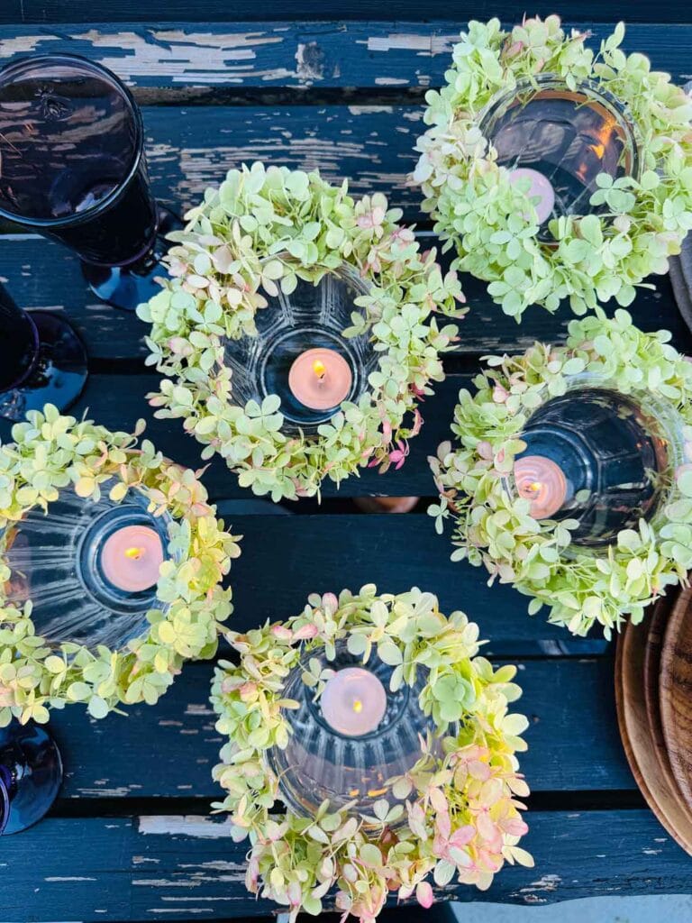 Five flower crown votives are prepared and burning on an old potting bench.