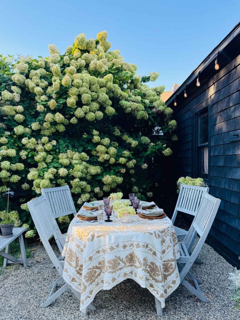 The sun is setting, a dinner table is set, and flower crown votives run down the middle of the table.