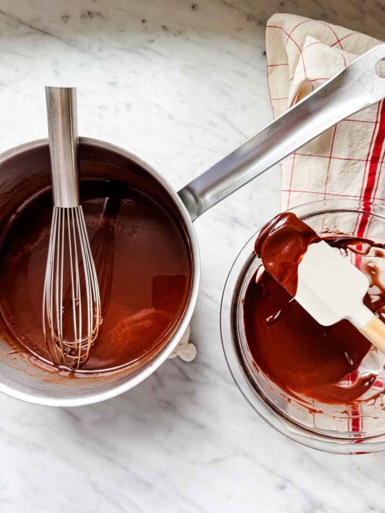 Pot of melted chocolate with whisk, glass bowl with chocolate. 