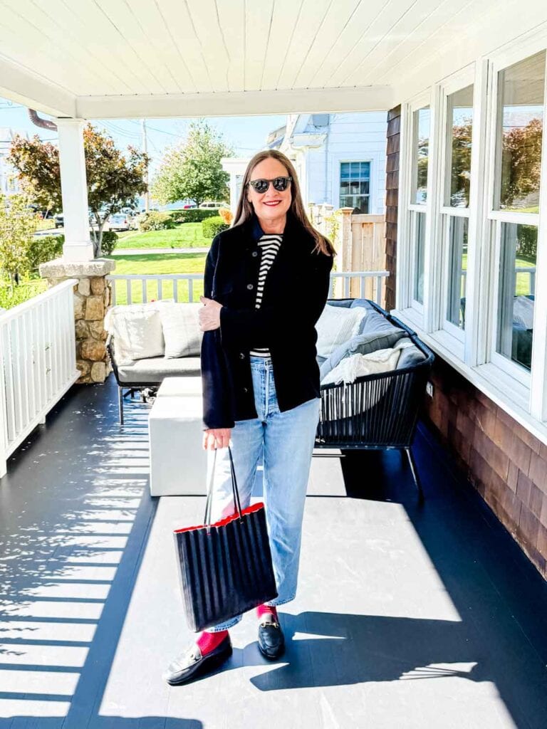 Annie Diamond wearing jeans, black wool chore coat, loafers.