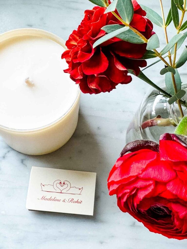 A candle and matches are sitting next to a small jar of flowers.