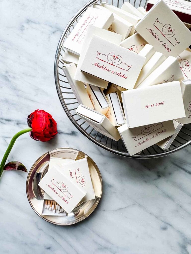 A silver bowl and a tip tray hold customized matchbooks for a wedding.