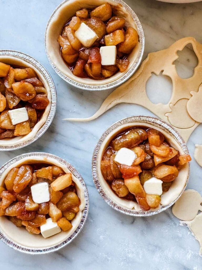 Mini apple pies dotted with cubed butter. 